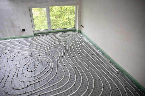 Shot of construction site in a loft where underfloor heating has just been installed, white pipes on grey mat