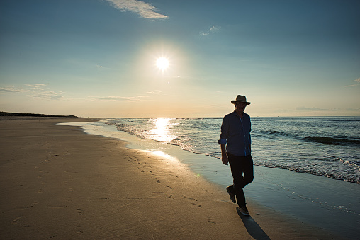Male walker with hat on the evening beach of Langeoog, sunset, backlight shot, golden hour