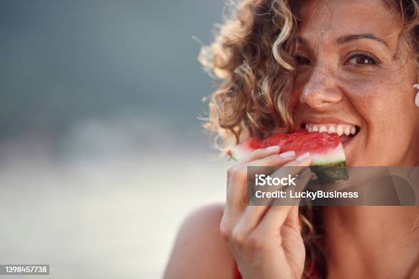 Beautiful Young Woman With Curly Hair Biting On Watermelon Piece Summertime Holiday Lifestyle Concept Stock Photo - Download Image Now