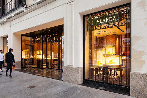 Madrid, Spain - 26th April 2022. Shop front of the Suarez luxury jewellery shop in Calle Serrano, Madrid, Spain. Two young men are walking past, looking in the window. Suarez is a Spanish company, headquartered in Valencia.