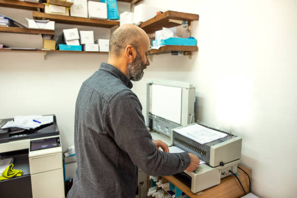 istock Caucasian man working at the copy shop, on a printing press 1398460227