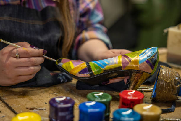 Unrecognizable Caucasian female artist, paint the high heels with paint, while working at the shoemaker workshop