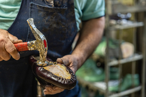 Unrecognizable Caucasian male shoemaker making shoes at this workshop