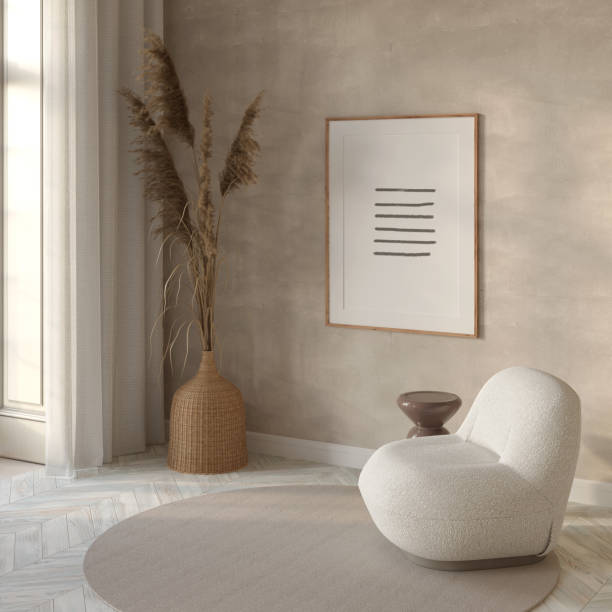 Modern sunny interior in light beige tones with a vertical poster over a white modern armchair with a beige coffee table, dried flowers in a wicker vase near the window with linen curtains.