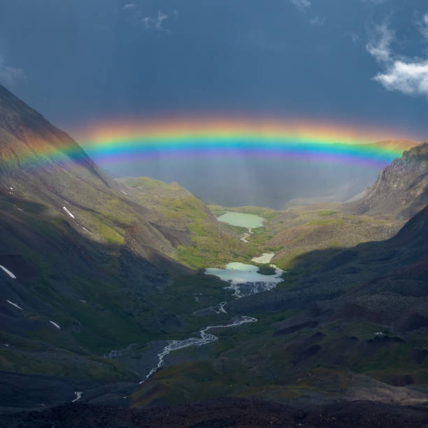 istock Rainbow over a mountain valley. Atmospheric alpine landscape with snowy mountains with rainbow in rainy and sunny weather. 1398463849