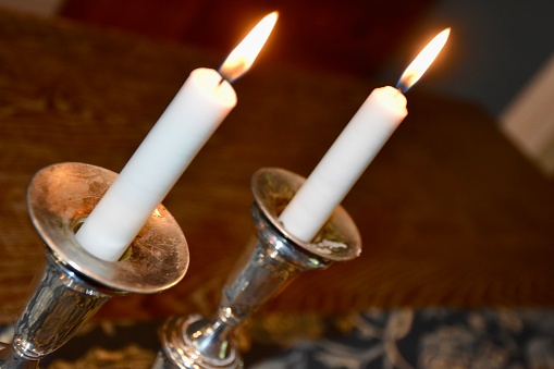 Two lit shabbat candles in silver candlesticks