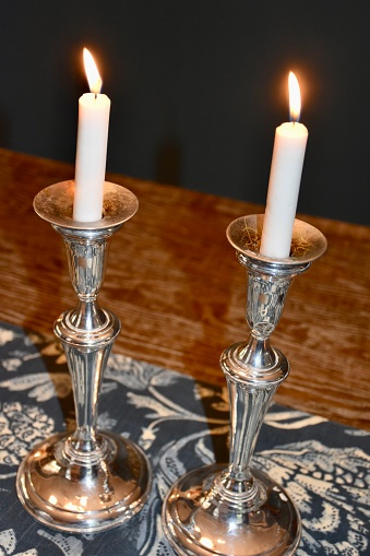 Metal retro candlestick with five burning candles against a dark background in the room home, selective focus. Horizontal Image for design with place for your text