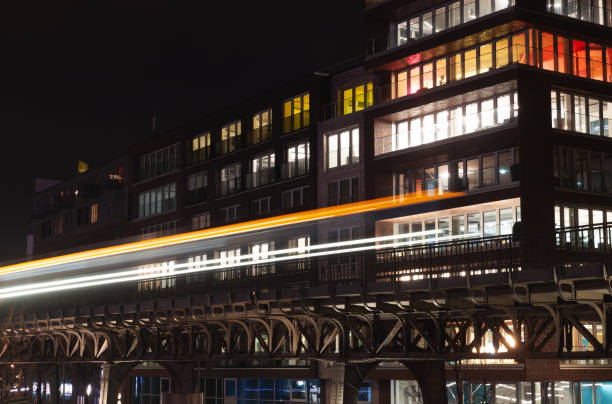 Night city view with illuminated windows of modern residential house and bright blurred headlights trails