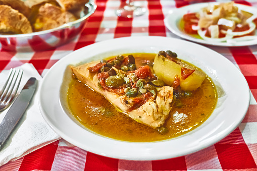 Stockfish (white/ without tomatoes) in Messina style. Cod stewed with cherry tomatoes, caper, olive oil and potato. Traditional plate of Messina, Sicily, Italy