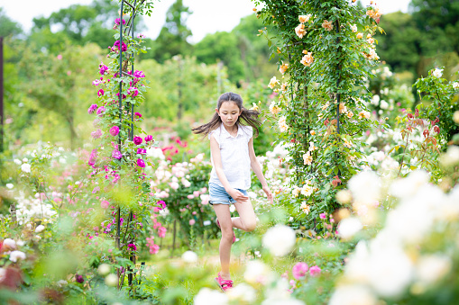 Girl playing in a rose bloomed garden