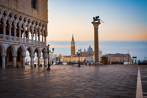 The sun rising behind the Doge's palace and column of St Mark's Square with the church of San Giorgio Maggiore in the distance.