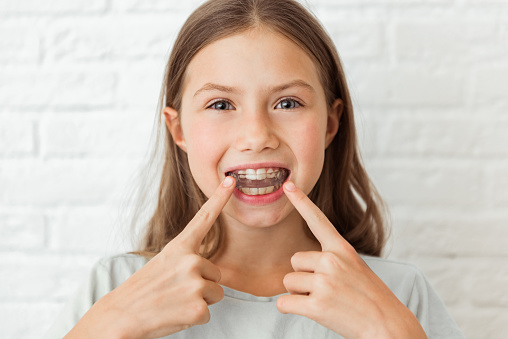 Atractiva niña muestra dedos índices entrenador miofuncional. Ayuda a igualar los dientes en crecimiento y corregir la mordida, desarrolla el hábito de respiración bucal. Corrige la posición de la lengua photo