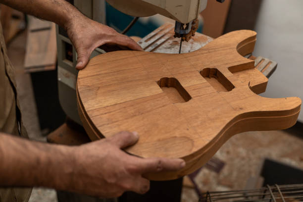 primer plano del irreconocible luthier latinoamericano haciendo una guitarra eléctrica con una sierra. concepto de construcción de instrumentos de cuerda - fabricante de instrumentos fotografías e imágenes de stock