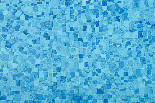 Top view of surface caustics ripped water in swimming pool and flow with waves background. Mosaic wall in blue color for copy space abstract backdrop.