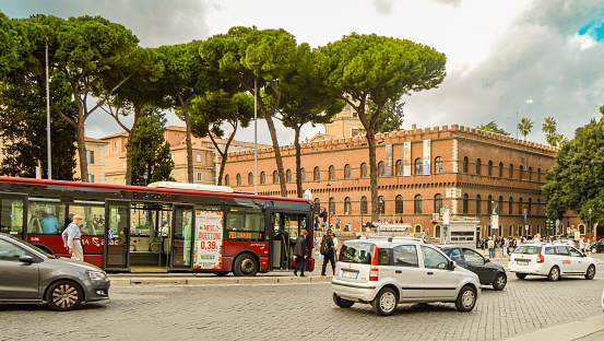 ROME, ITALY - OCTOBER 07, 2018: Red passenger bus and passenger car transport on Rome street in the central part of the city.