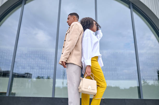 istock Girl and boy standing with backs to each other 1398489199