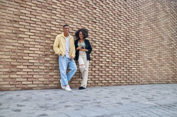 istock Boy and girl looking at camera near brick wall 1398489227