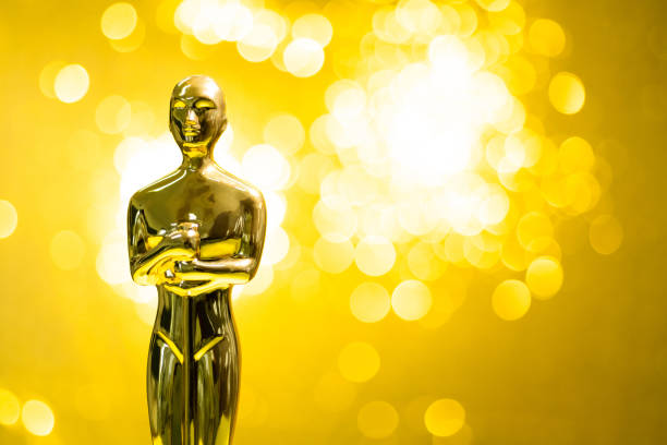 golden statuette on shiny yellow background - oscar statuette imagens e fotografias de stock