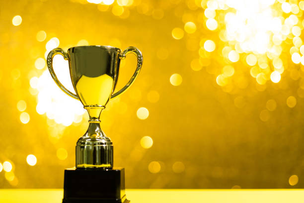 Golden trophy on shiny yellow background.