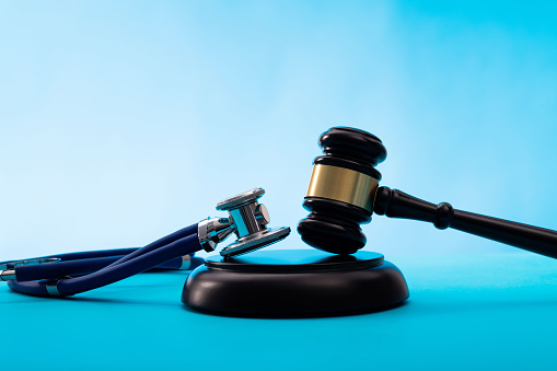 Gavel and stethoscope on blue table.