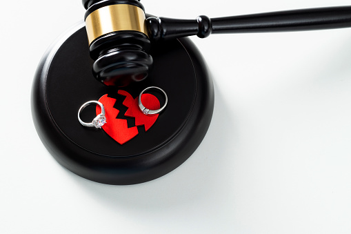 Gavel with broken heart and rings on white background.