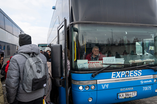 Lviv, Ukraine - March 93 2022: People board a bus outside the Lviv train station bound for Krakow, Poland