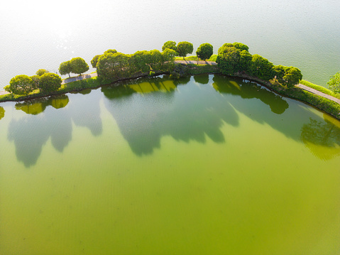 Drone point of view footpath in the middle of public park lake during sunset