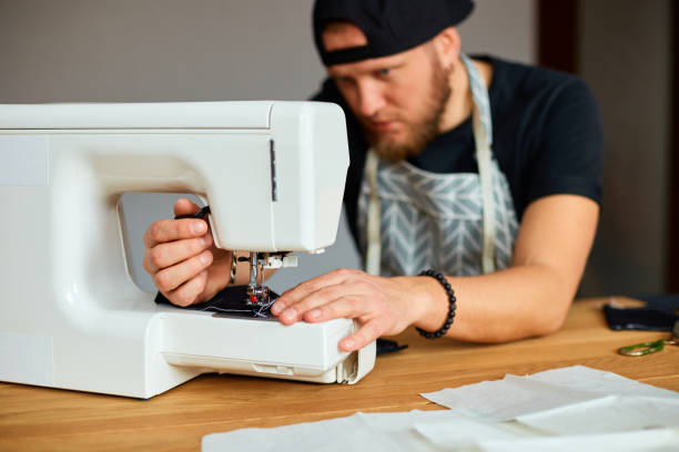 istock Man sews clothes on sewing machine,  male tailor working with sewing in atelier, textile industry, hobby, workspace, small busines. Creation process DIY, Workplace of seamstress. 1398497463