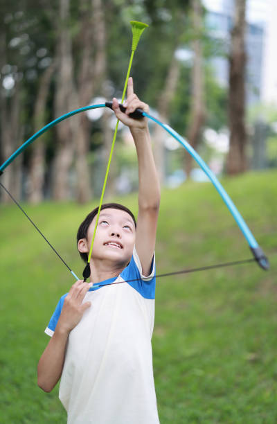 One man, young archer with bow and arrow training alone outdoors in nature, part of.