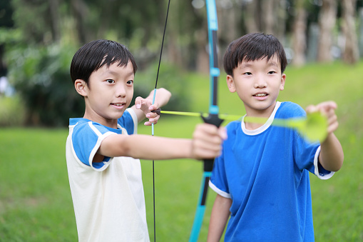 Little boy shooting bow in forest