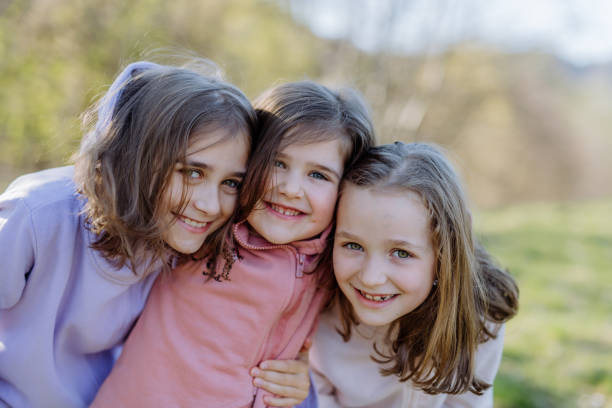istock Three little sisters looking at camera in spring nature together. 1398499305