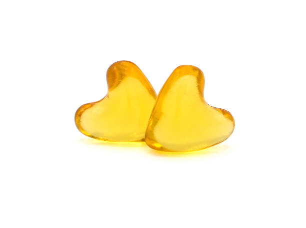 Close up of natural extraction oil filled capsules (soft gel)  heart shape design isolated on white suitable for: rice bran and grem oil, omega 3, omega 6, omega 9, C6-C12, vitamin E, Clipping path. Close up of natural extraction oil filled capsules (soft gel)  heart shape design isolated on white suitable for: rice bran and grem oil, omega 3, omega 6, omega 9, C6-C12, vitamin E, Clipping path. cod liver oil fish oil vitamin a pill stock pictures, royalty-free photos & images