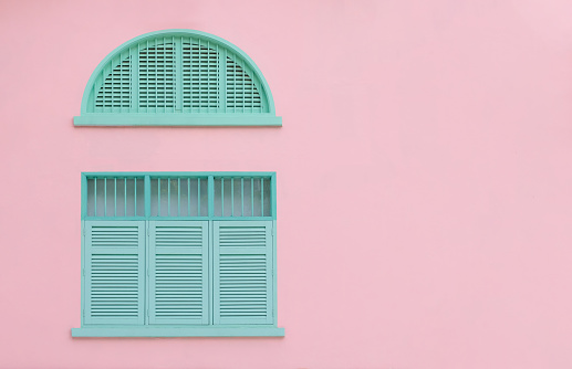 Vintage closed green mint shutters and wooden windows isolated on pink background with copy space and clipping path.