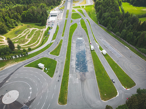 Aerial view, drone shoot, drone flying over safe driving center in the countryside. Car range was created for practicing safety driving in dangerous conditions, such as snow, rain… The main thing is to learn safety driving. This is a built facility for carrying out safety driving exercises. It is also appropriate for testing vehicles and how they perform in different weather conditions, such as snow, ice rain, slippery road. All the exercises are done in a safe environment.