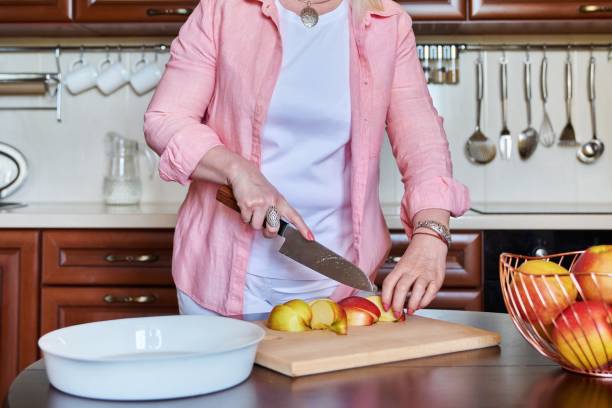 istock Woman's hand cutting apples with knife on wooden cutting board 1398510095