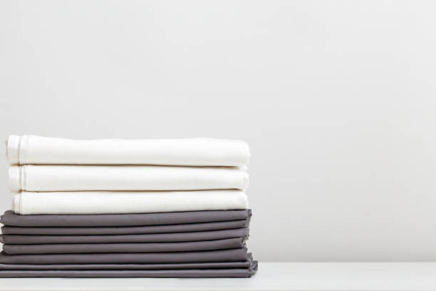 A stack of gray and white bed linens, sheets on the table. A stack of gray and white bed linens, sheets on the table. bed sheets stock pictures, royalty-free photos & images