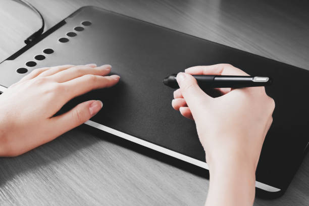 istock Female hands draw on a graphic tablet. Designer hand holds a pen and draws on a tablet 1398511921