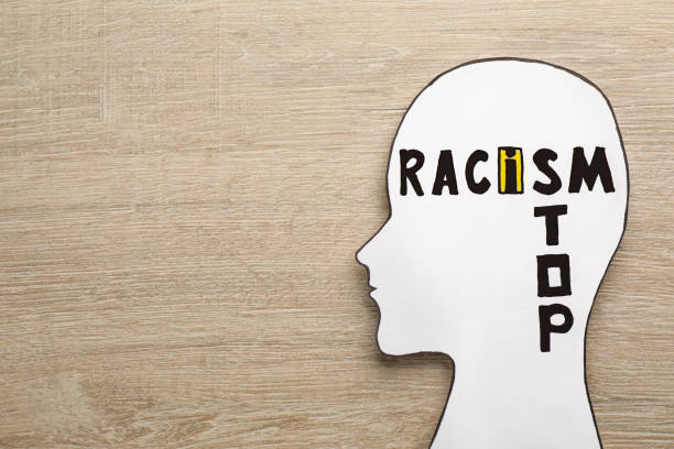 istock White head cutout with phrase Stop Racism on wooden table, top view. Space for text 1398514270