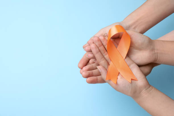 istock Couple holding orange ribbon on light blue background, top view with space for text. Multiple sclerosis awareness 1398514557