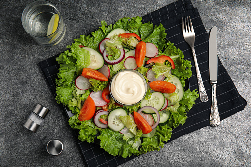 Plate of delicious vegetable salad with mayonnaise served on grey table, flat lay