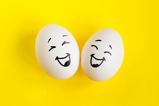 Two white eggs on yellow background concept. Emotions laughter and happiness. Friendship, relationship concept.