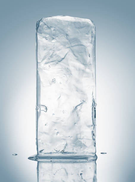 Crystal clear natural ice block in light blue tones on a white reflective surface.