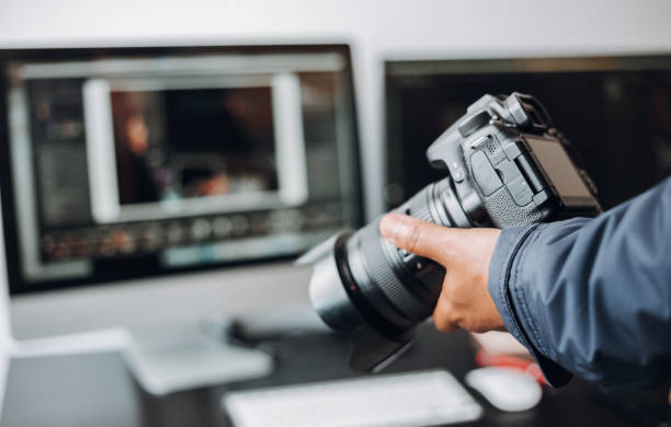 istock photographer hand camera and computer on desk 1398520477
