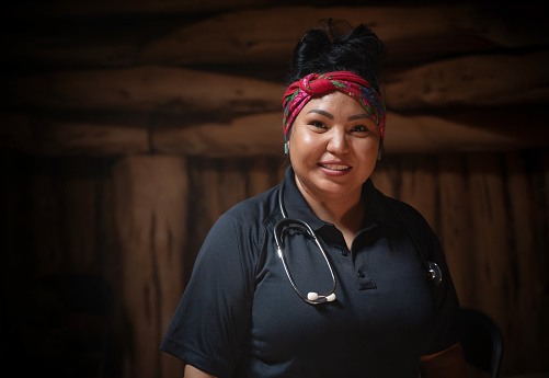 Portrait of Indigenous Navajo woman working as EMT / Paramedic visiting a hogan in Monument Valley