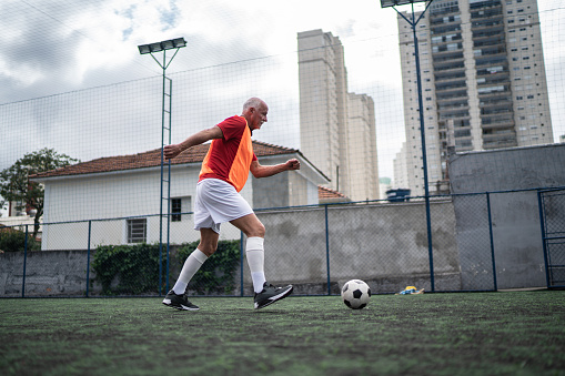 Senior man kicking a soccer ball on the soccer field