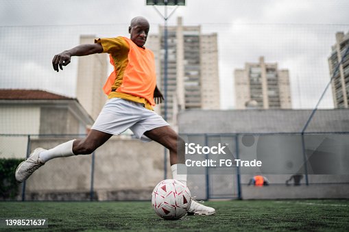 istock Mature man kicking the soccer ball on the soccer field 1398521637