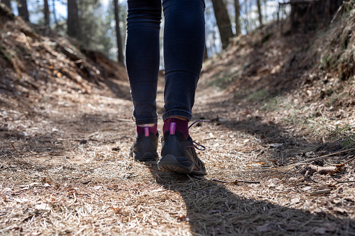 Woman feet walking alone along forest path. Back view of traveler shoes. Outdoor activities, going hiking or camping. High quality photo