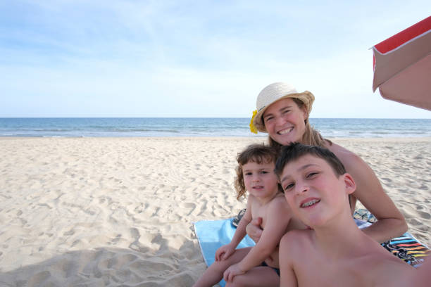 Brothers and sister are having splashing fun on beach in big waves. Children are aged 7 and 11. Costa del Sol, Andalusia, Spain.\n