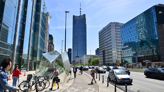 Warsaw, Poland. 16 May 2022. Glass skyscrapers against the blue sky and traffic in the city center. Colorful cityscape with buildings architecture and cars on the street. Sunny weather in the city.