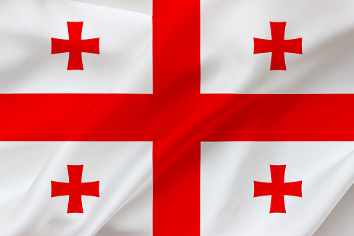 Gorgia flag on waving silk background. Fabric texture. National icon of Georgia.